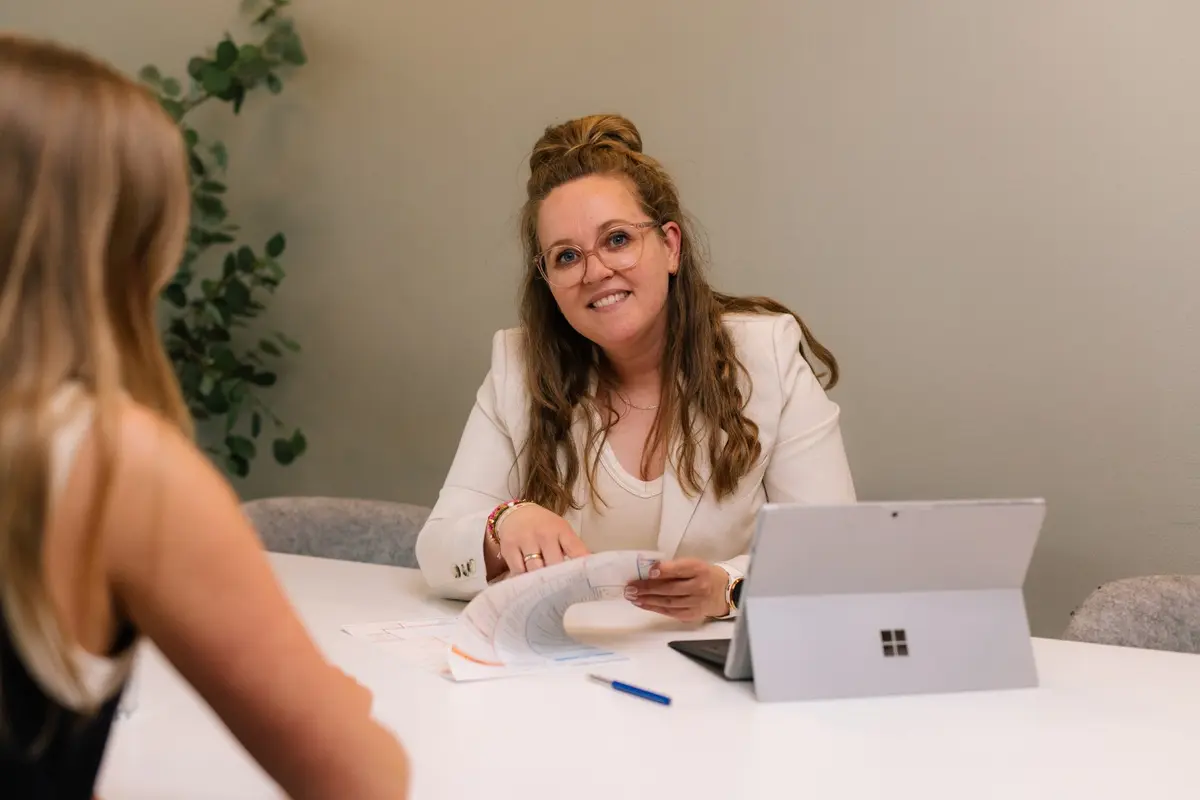 Adviseur en klant kijken samen naar een laptopscherm aan tafel