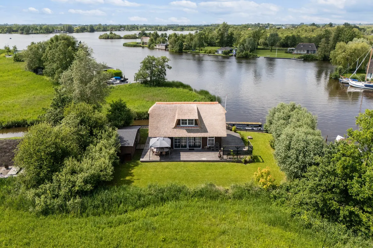 Zeilschip op een Fries vaarwater langs een begroeide oever