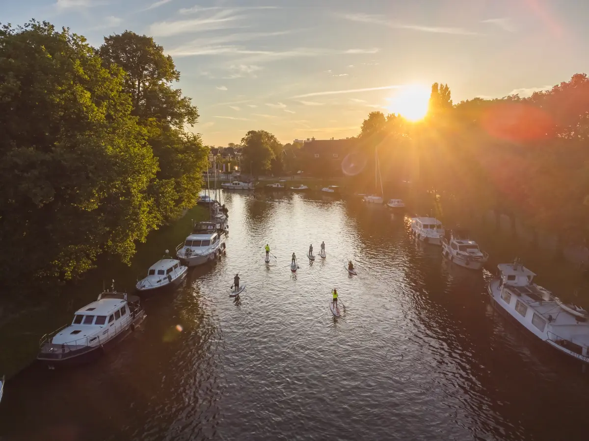 Suppers op een Friese vaart tussen de aangemeerde boten, gezien vanuit de lucht in de avondzon